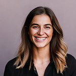 Smiling woman with long brown hair wearing a black shirt against a gray background.